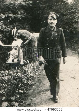 SAMBIR, Ukrajina, CIRCA třicátých let - vinobraní fotografie muže v uniformě s mladou matkou a dítětem v zádech