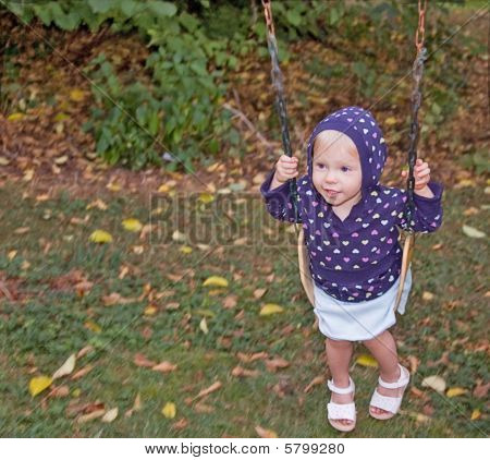 Bambina oscillanti sul giorno di autunno