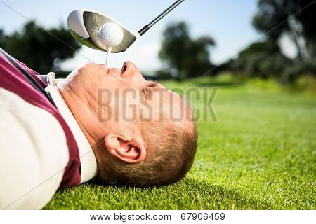 Golfer holding tee in his teeth on a sunny day at the golf course