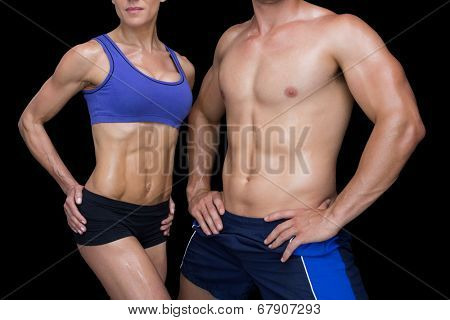 Crossfit couple posing with hands on hips on black background