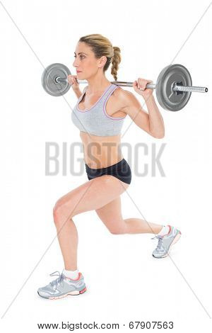 Serious female crossfitter lifting barbell behind head on white background