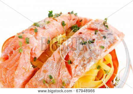 fresh fried natural pink salmon on italian traditional tagliatelle backed with tomato and vegetables isolated over white background