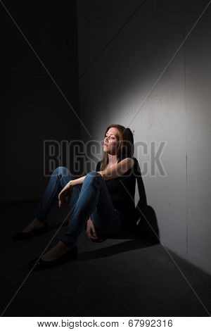 Young woman suffering from a severe depression (very harsh lighting is used on this shot to underline/convey the gloomy mood of the scene)