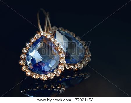 Gold Ear Rings Against A Dark Background.