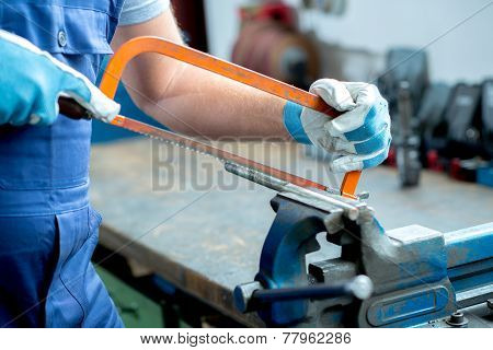 worker with saw on work bench in the factory