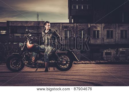 Biker and his bobber style motorcycle on a city streets 