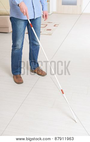 Blind man with white stick and dark glasses at home