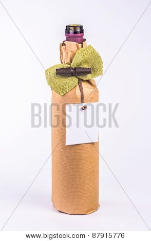 isolated bottle wrapped in paper decorative bow and white card