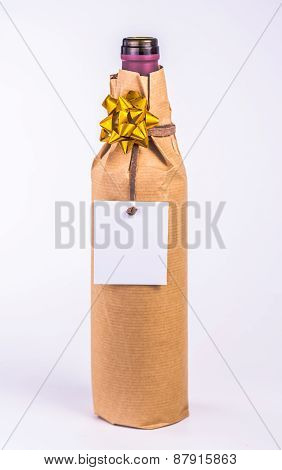 isolated bottle wrapped in paper with golden bow and white card