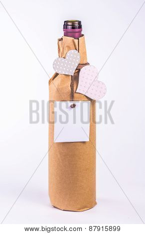 isolated bottle wrapped in paper with paper hearts and card
