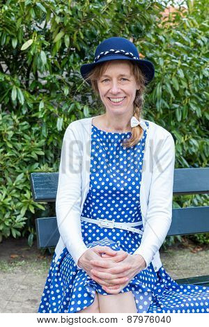 Woman in old-fashioned dress sitting on bench in park