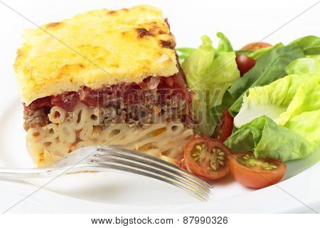 Greek pastitsio pasta topped with minced beef, tomatoes, bechamel sauce and cheese, served with a salad.