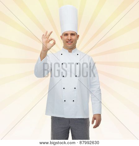 cooking, profession, gesture and people concept - happy male chef cook showing ok sign over yellow burst rays background