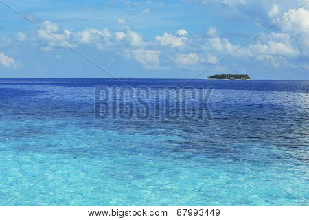 View of beautiful blue ocean water and island on horizon in Baros Maldives