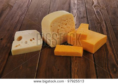 various types of fresh raw aged delicatessen cheese on wooden table cheddar edam swiss