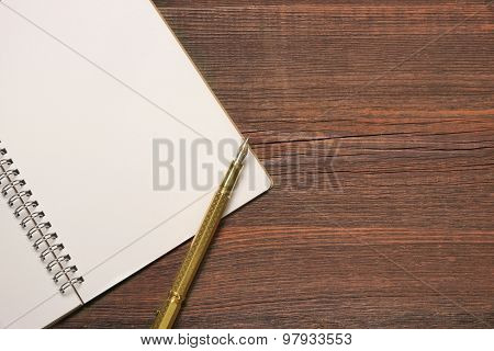 Open Spiral Bound Notebook With White Pages And Gold Pen.