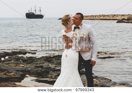 Beautiful  Gorgeous Blonde Bride  And Stylish Groom Kissing, On The Background Of A Sea, Wedding