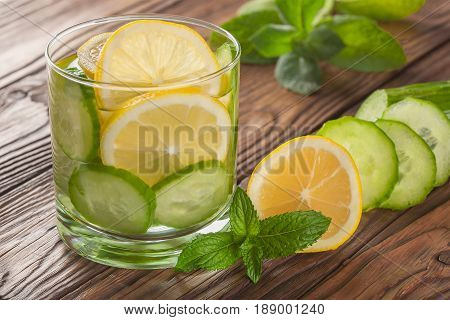cool drink with lemon and mint on a wooden background