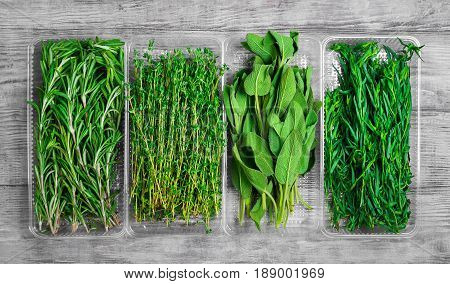 Assortment of fresh herbs for meat and fish tarragon parsley rosemary thyme sage. Light white wooden background. Top view.