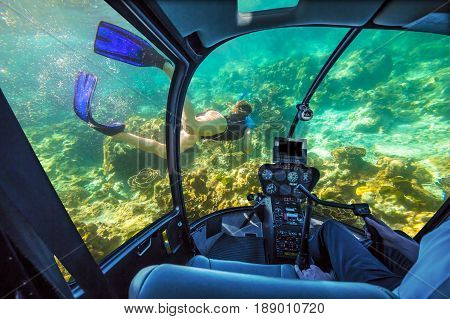 Underwater submarine ship following a woman in apnea swimming in tropical turquoise sea of Racha Noi, Phuket in Thailand. cockpit interior view. Undersea background. Travel concept.