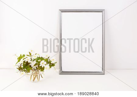 Silver frame mockup with blooming Rue Anemone. Empty frame mock up for presentation artwork. Template framing for modern art.