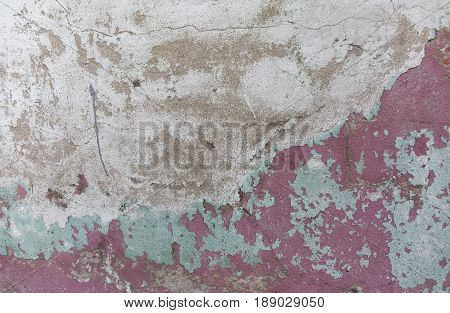 Old painted wall. Green and pink damage surface. Peeling paint background. Stone demaged backdrop