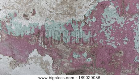 Old painted wall. Green and pink damage surface. Peeling paint background. Stone demaged backdrop