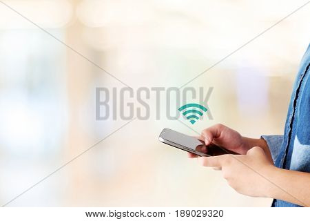 Hand using smart phone and wifi icon over blur background with copy space digital network technology concept