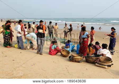 PURI INDIA - 19 DECEMBER 2009: Poor Indian fishermen along with families are waiting on the beach for the boats returning from the fishing