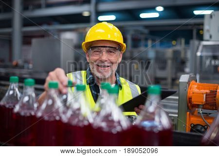Portrait of male factory worker monitoring cold drink bottles at drinks production factory