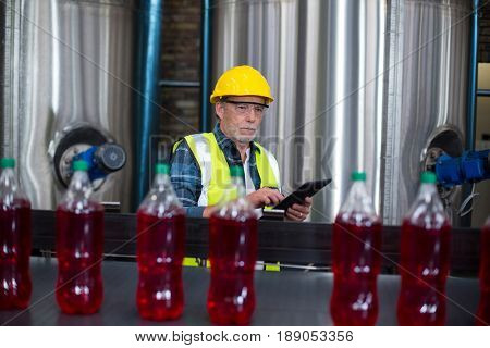 Male factory worker monitoring cold drink bottles at drinks production factory