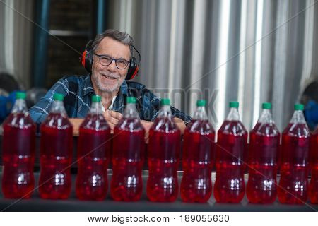 Portrait of male factory worker monitoring cold drink bottles at drinks production factory