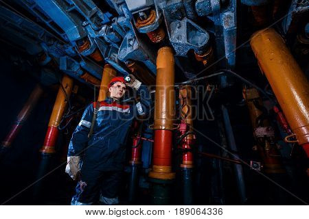 young coal miner is underground in a mine for coal mining in overalls against the backdrop of mining equipment. Portrait.