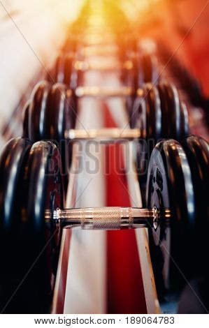 Sports equipment dumbbell rests in a row.  hign contrast and monochrome color tone