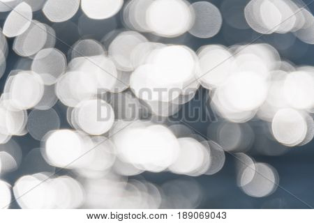 Water bokeh background. Defocused water surface with waves glittering in the sun.