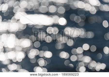 Water bokeh background. Defocused water surface with waves glittering in the sun.