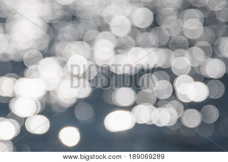 Water bokeh background. Defocused water surface with waves glittering in the sun.