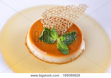 dessert cream brulee on the plate decorated with mint and caramel. top view