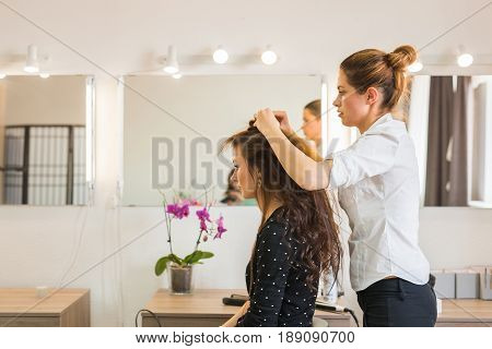 working day inside the beauty salon. Hairdresser makes hair styling.