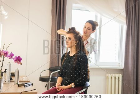 working day inside the beauty salon. Hairdresser makes hair styling.