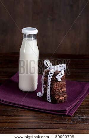 Glass Bottle Of Milk With Brownie Cakes With White Ribbon On Napkin At Tabletop