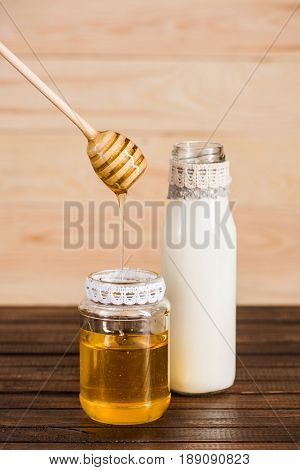 Glass Bottle Of Milk With Honey In Jar On Wooden Background
