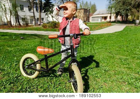 Boy with balane bike on green lawn in park during day