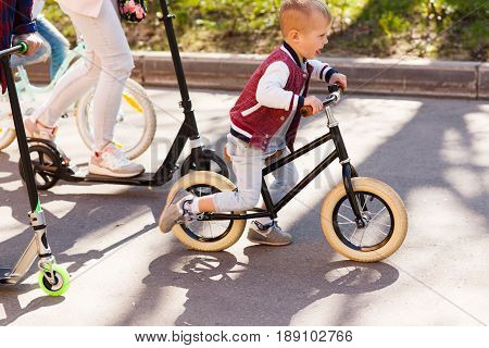 Walking family on cycles in spring park afternoon