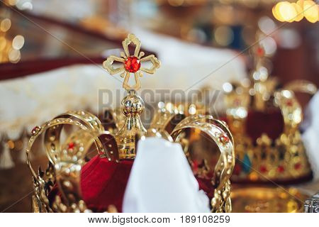 Golden wedding crowns with precious stones lying on the table in the church