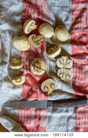 Close up fresh mushrooms cut in halves and old knife lying on cloth for abstract background