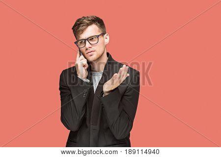 The young caucasian businessman in glasses on red studio background talking on cell phone