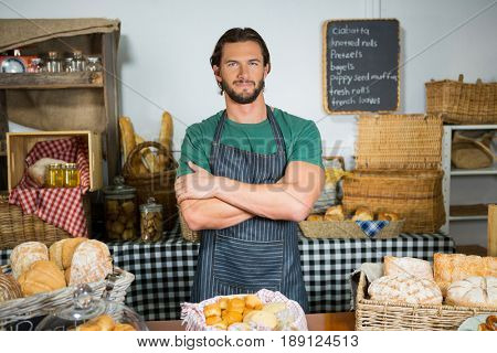 Portrait of staff standing with arms crossed at counter in bakery shop