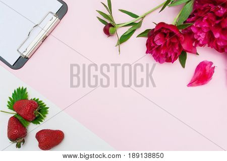 Peonies and strawberries on a pink background
