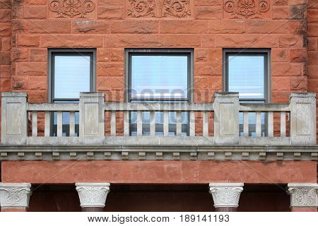 Close up on the windows pillars balcony and red sand-stone bricks of a historic old Building.
